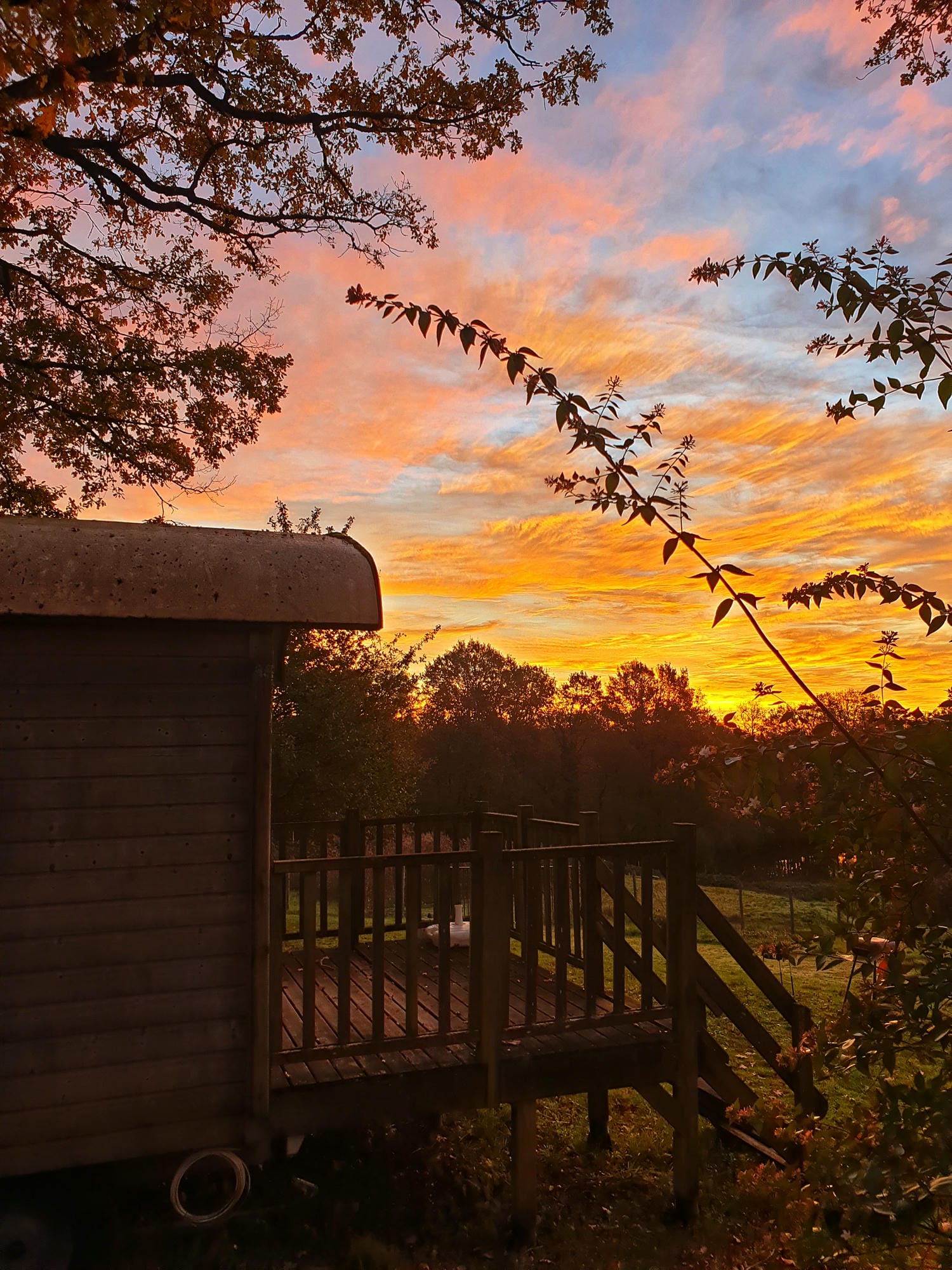 Coucher de soleil sur une roulotte de charme dans un champ arboré au Camping Château le Verdoyer