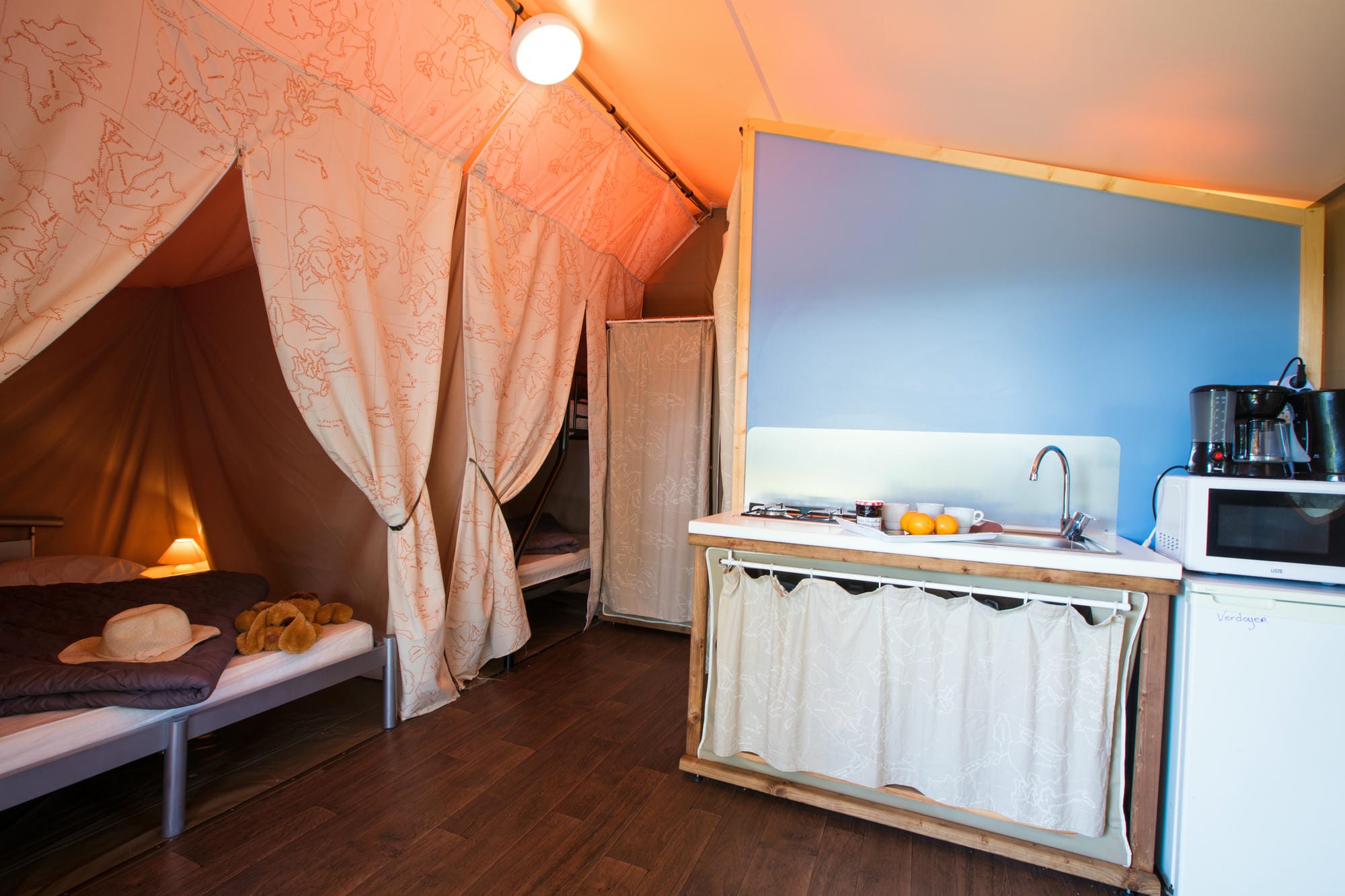 Coin cuisine avec micro-ondes et lit dans une tente lodge au Château le Verdoyer