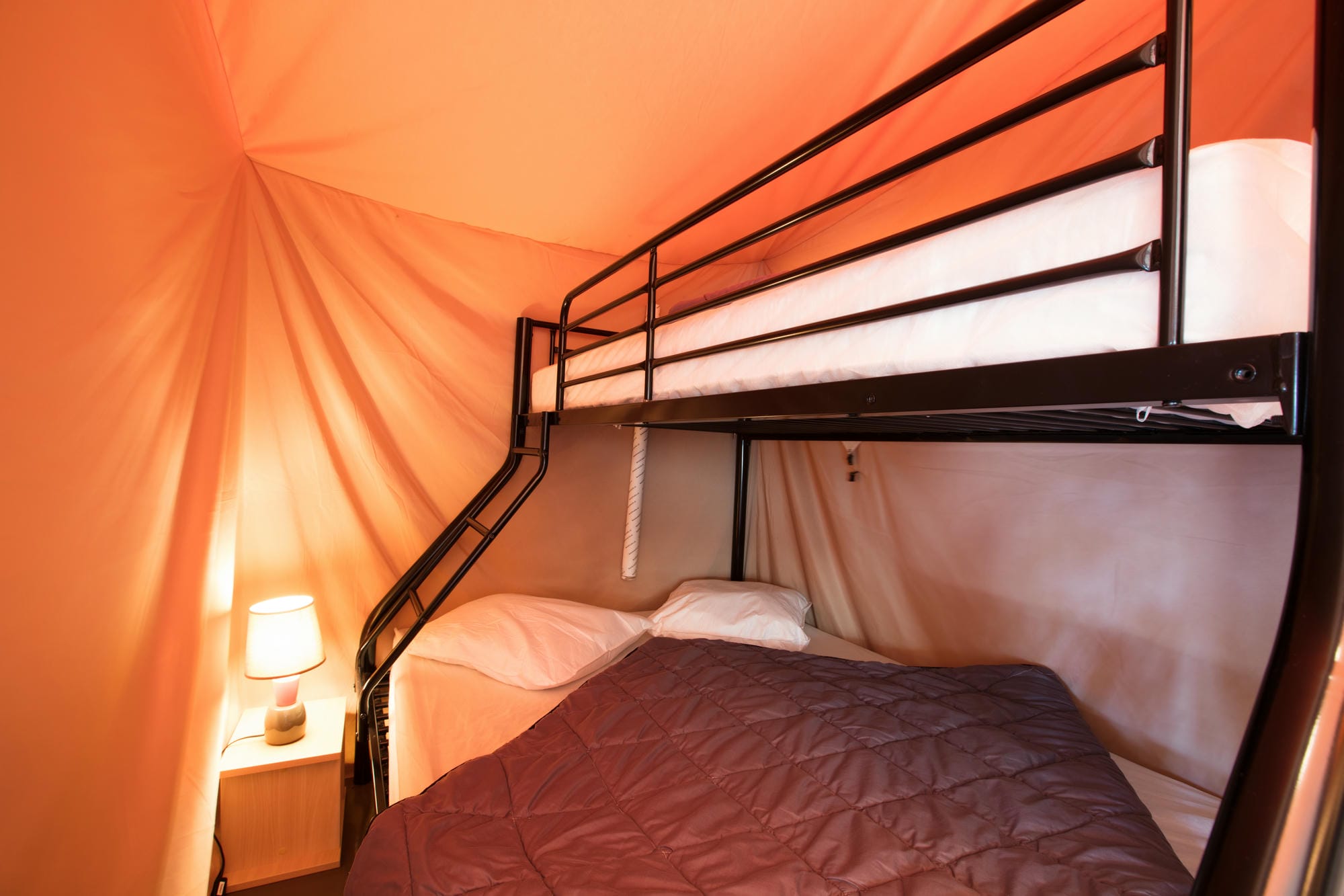 Lits superposés avec couverture et lampe dans une tente lodge familiale au Verdoyer