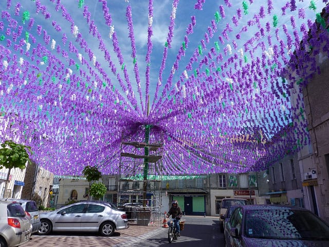 Décorations florales en papier coloré de la Félibrée du Périgord ornant une place de village, fête occitane à découvrir depuis le Château le Verdoyer
