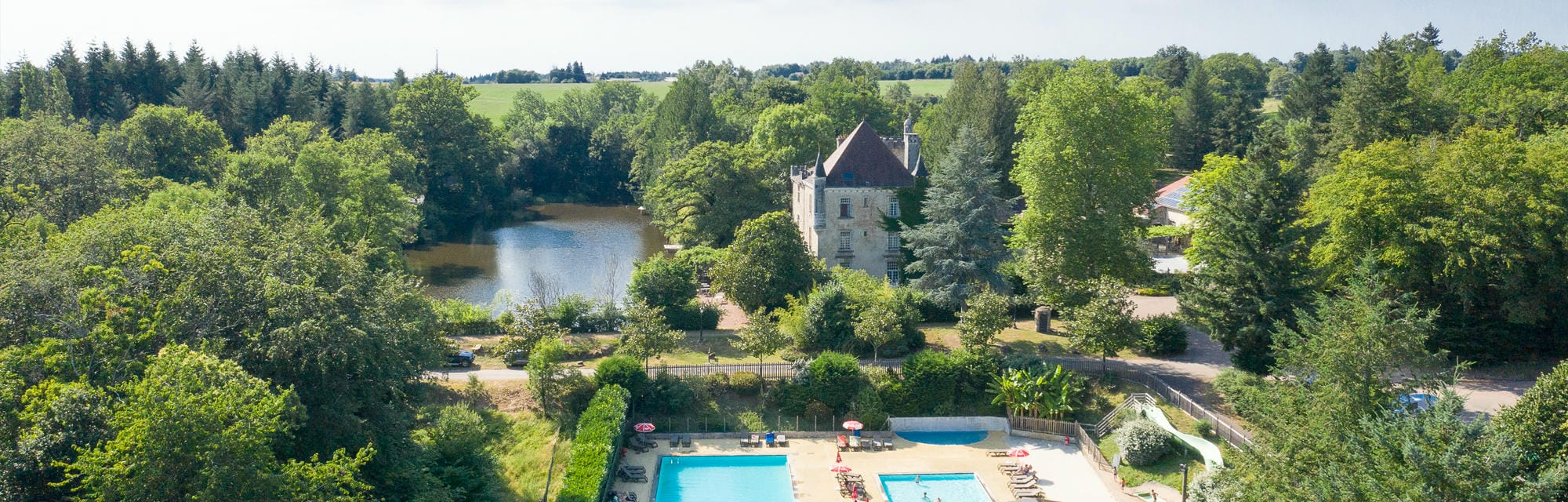 Vue aérienne de la piscine et du Château le Verdoyer, domaine arboré en Dordogne