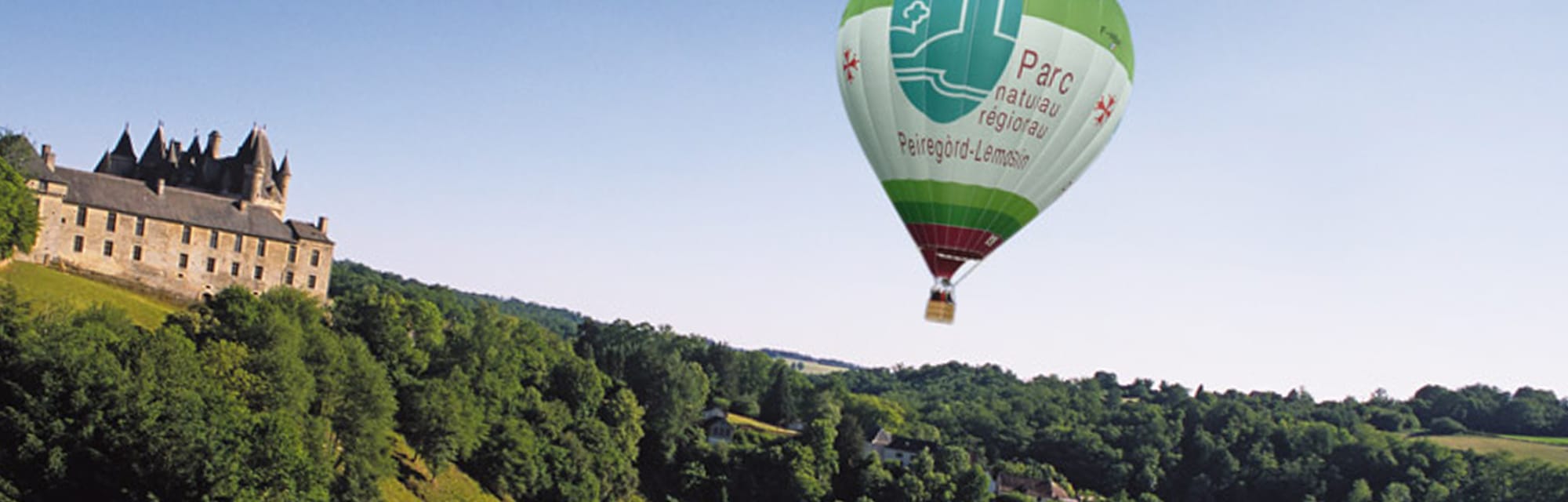 Montgolfière survolant le château de Jumilhac sur une colline, Parc Naturel Régional Périgord-Limousin
