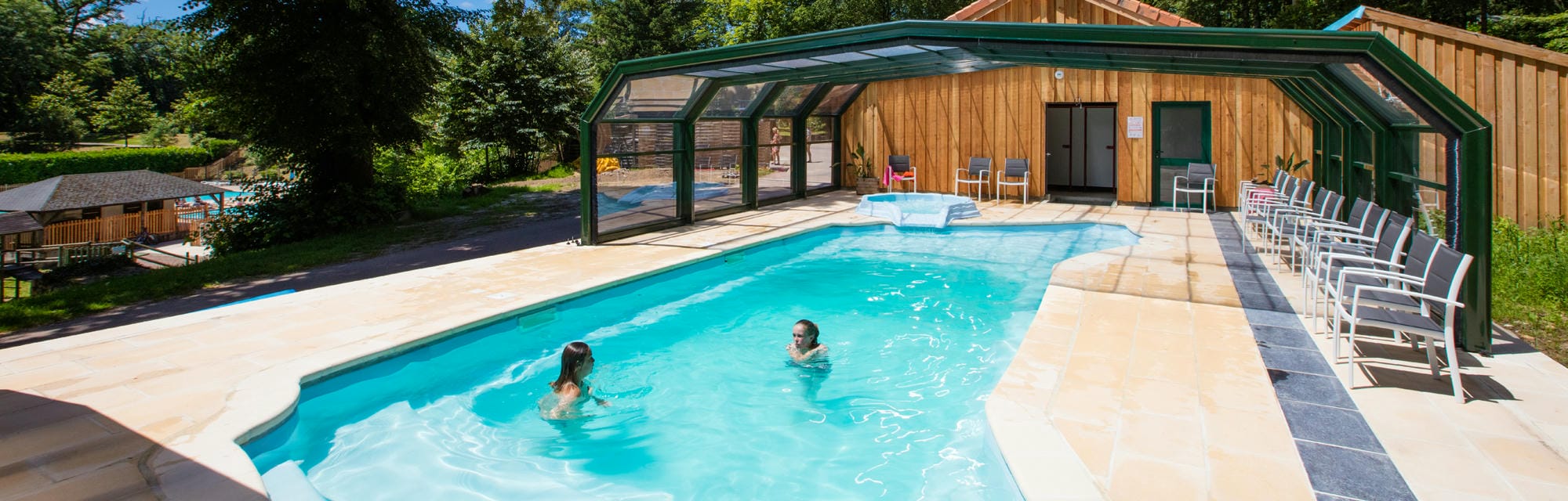 Couple nageant dans la piscine extérieure du Camping Château le Verdoyer