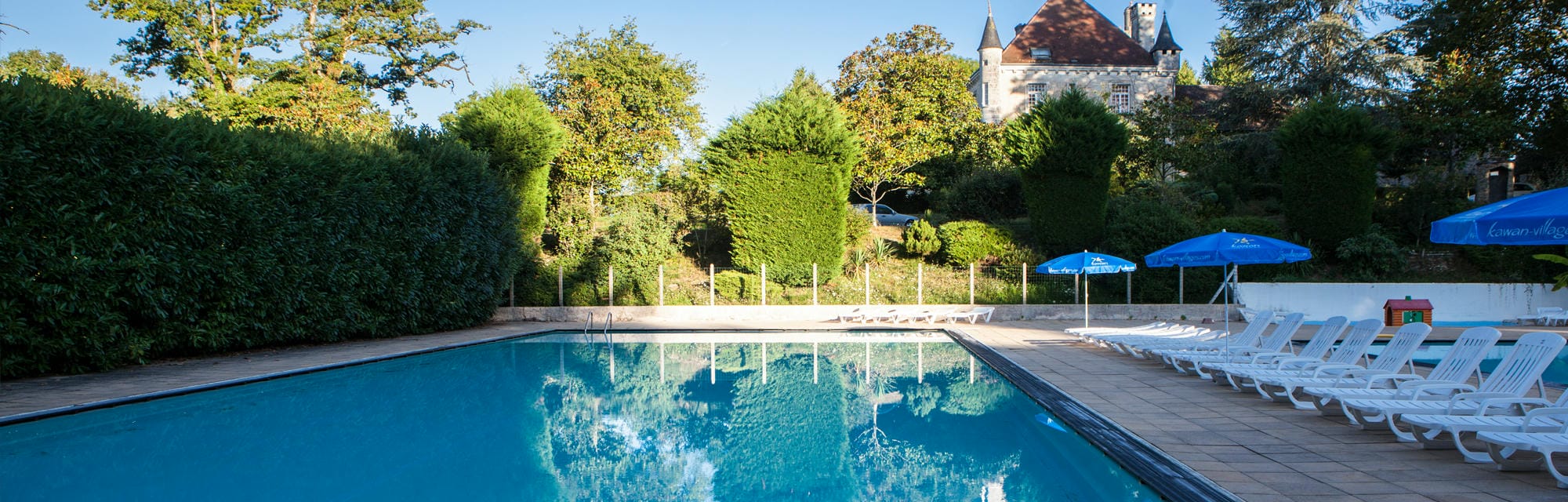 Nombreux transats et parasols autour de la piscine extérieure du Camping Château le Verdoyer