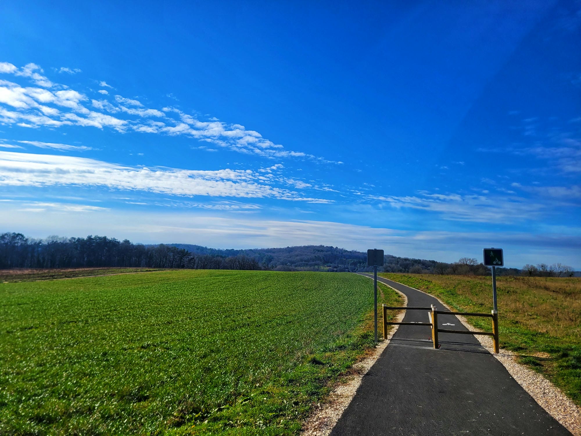 Route longeant un champ avec un panneau indicateur, Flow Vélo en Périgord Vert