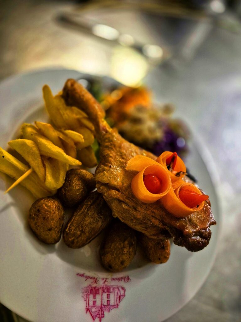 Confit de canard doré avec pommes de terre sarladaises et décoration de roses en carotte, spécialité périgordine au restaurant du Château le Verdoyer