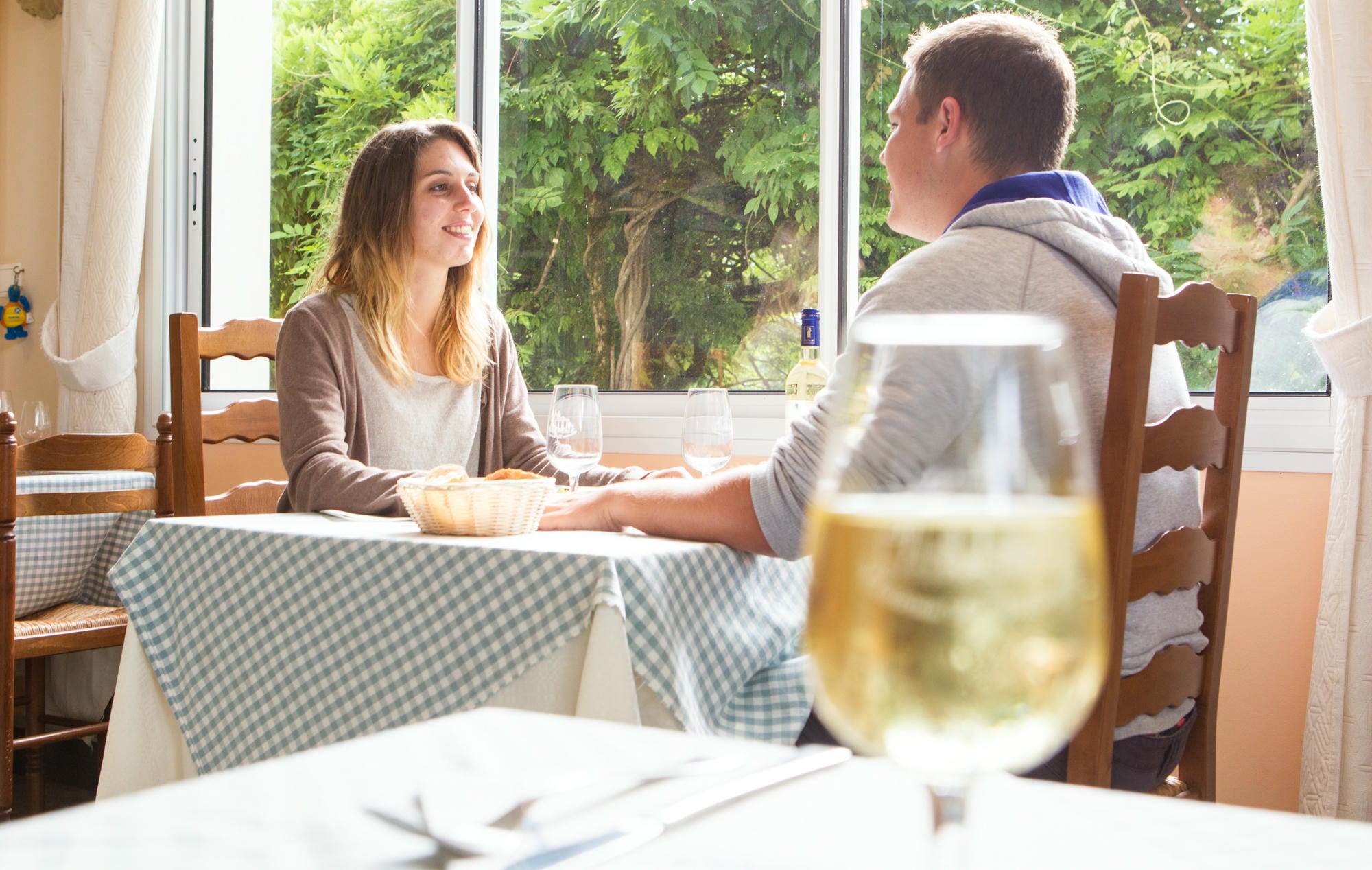 Couple attablé avec un verre de vin en salle avec vue sur étang du restaurant du Château le Verdoyer