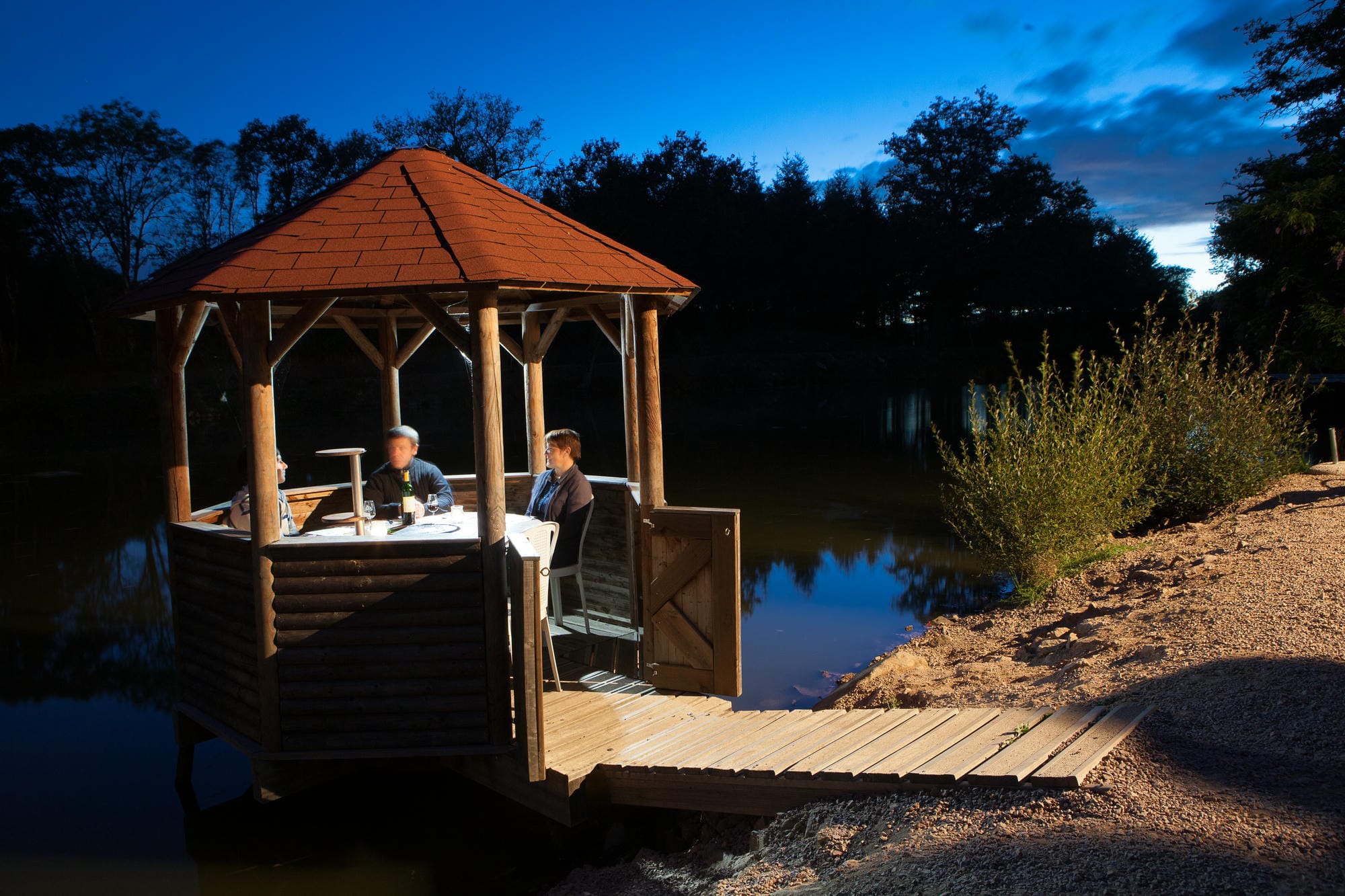 Couple à table sur un ponton au bord de l'étang, dîner romantique au Château le Verdoyer