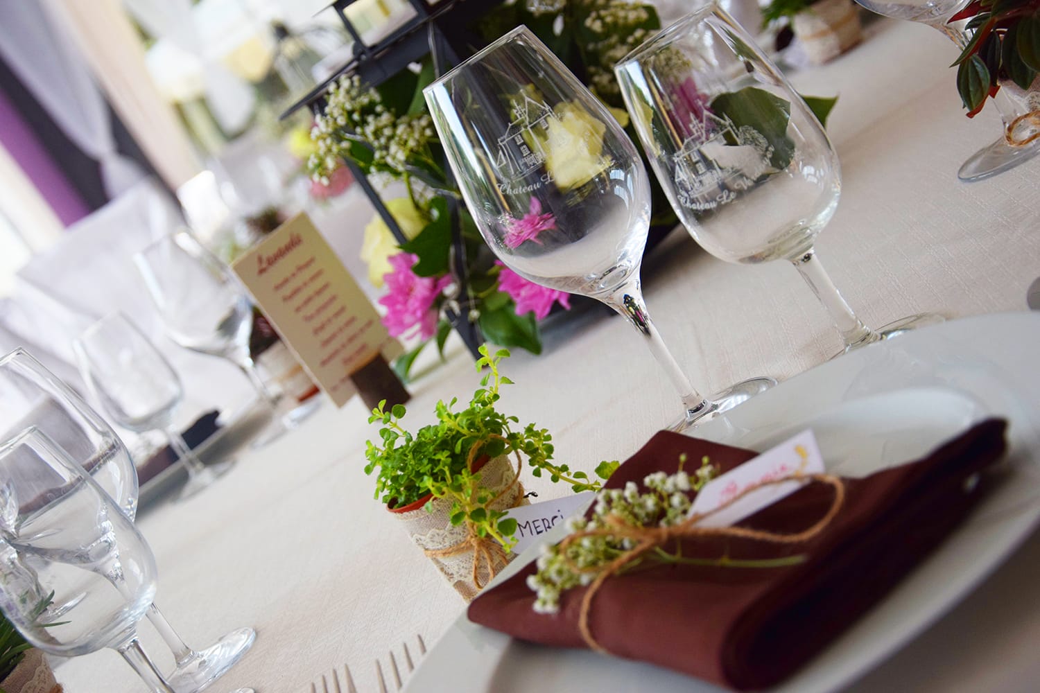 Nombreux verres à vin et compositions florales sur une table de banquet de mariage au Verdoyer