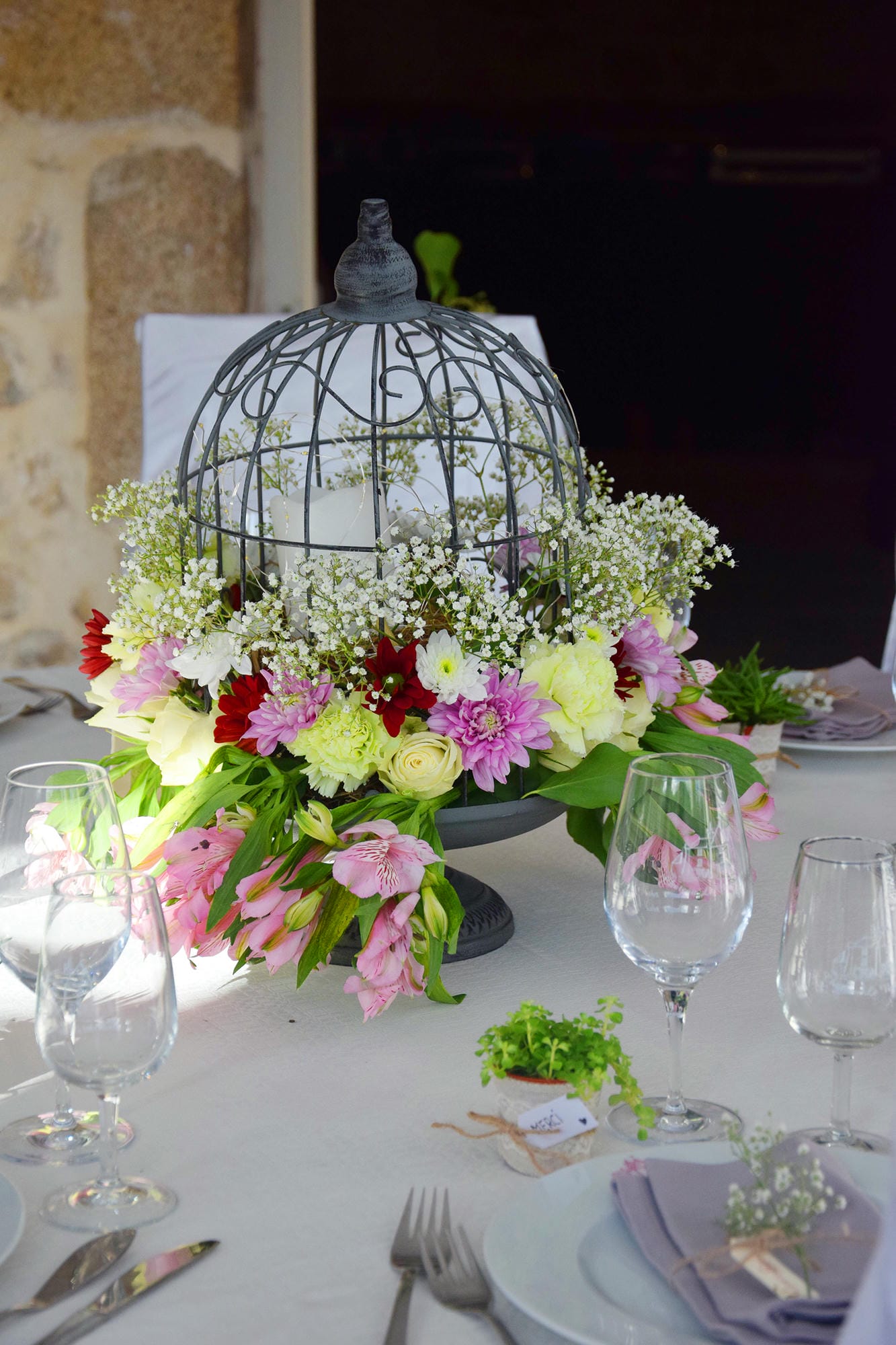 Cage à oiseaux décorative avec fleurs sur une table de mariage dressée au Château le Verdoyer