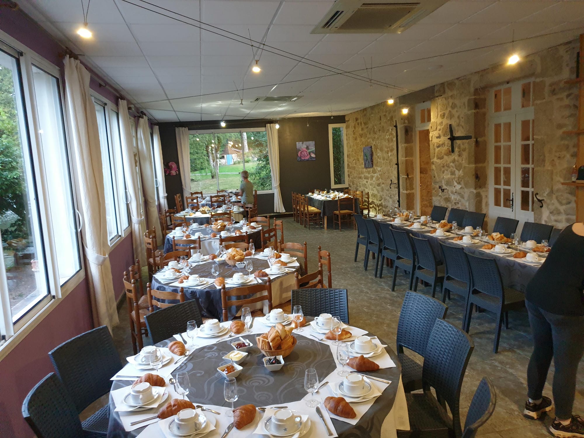 Tables dressées pour un repas de mariage avec vue sur l'extérieur, restaurant du Château le Verdoyer