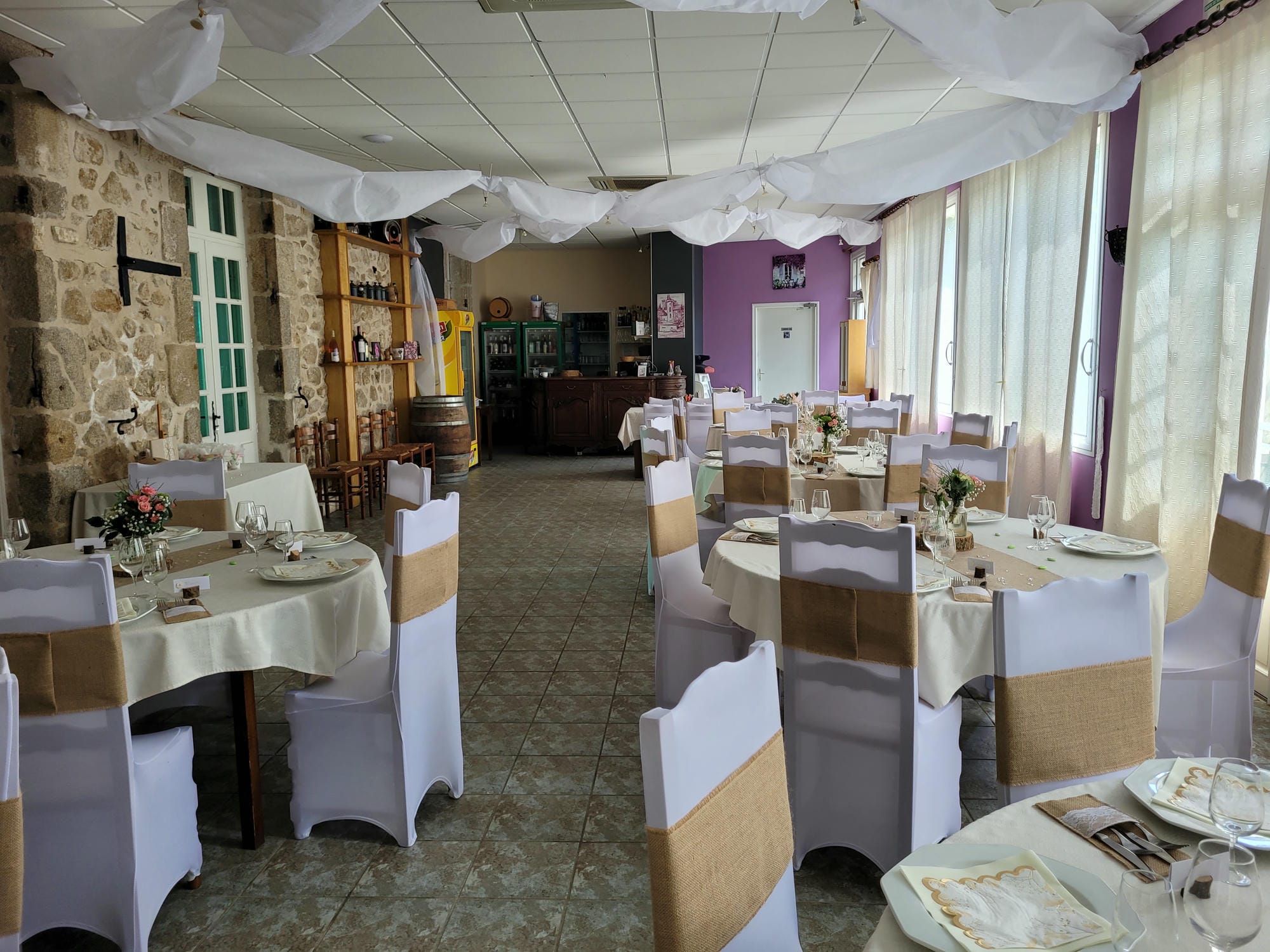 Tables et chaises dressées avec linge blanc dans la salle de réception du Château le Verdoyer pour un mariage
