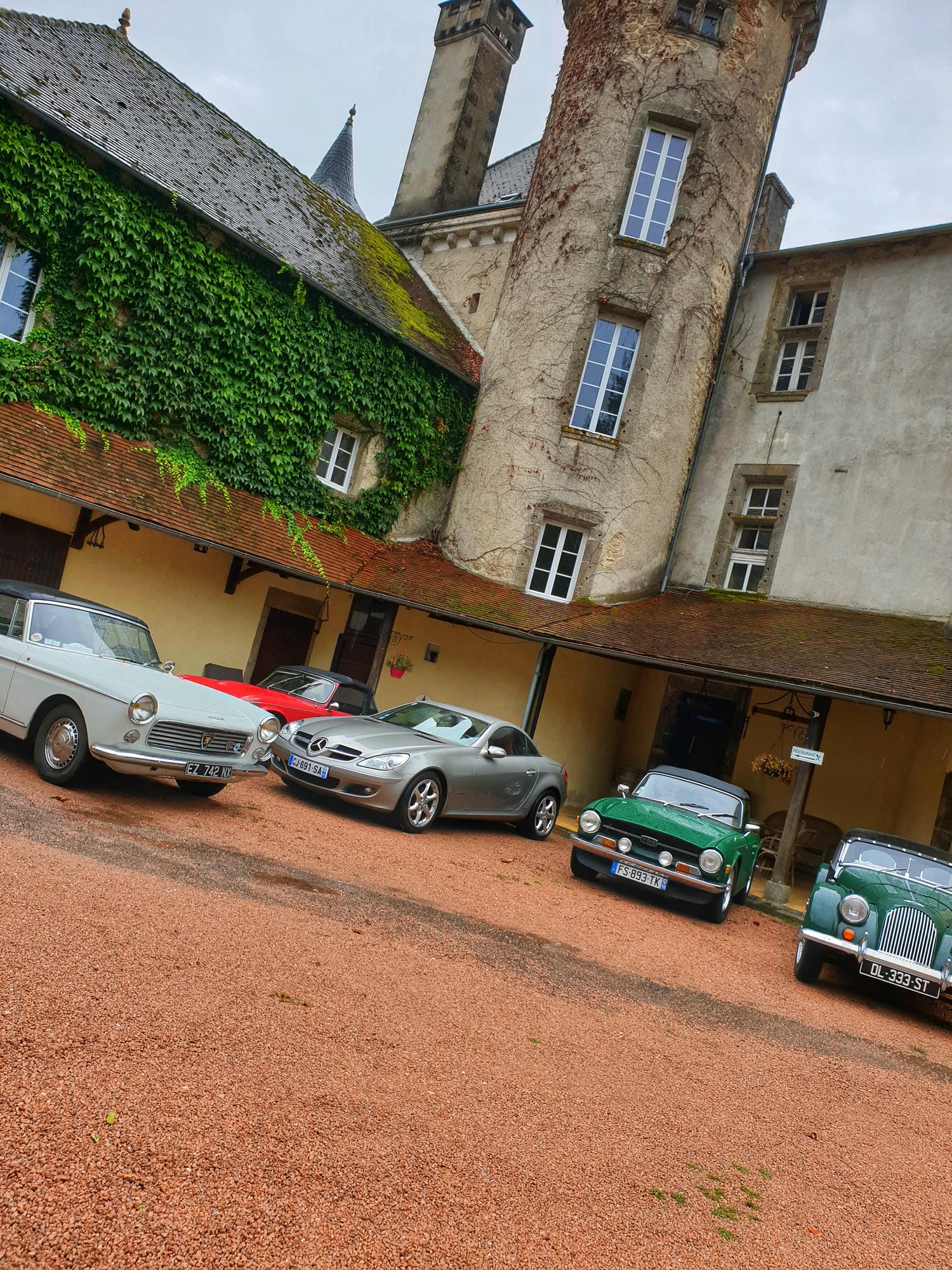 Plusieurs voitures de collection garées devant le Château le Verdoyer et sa tour