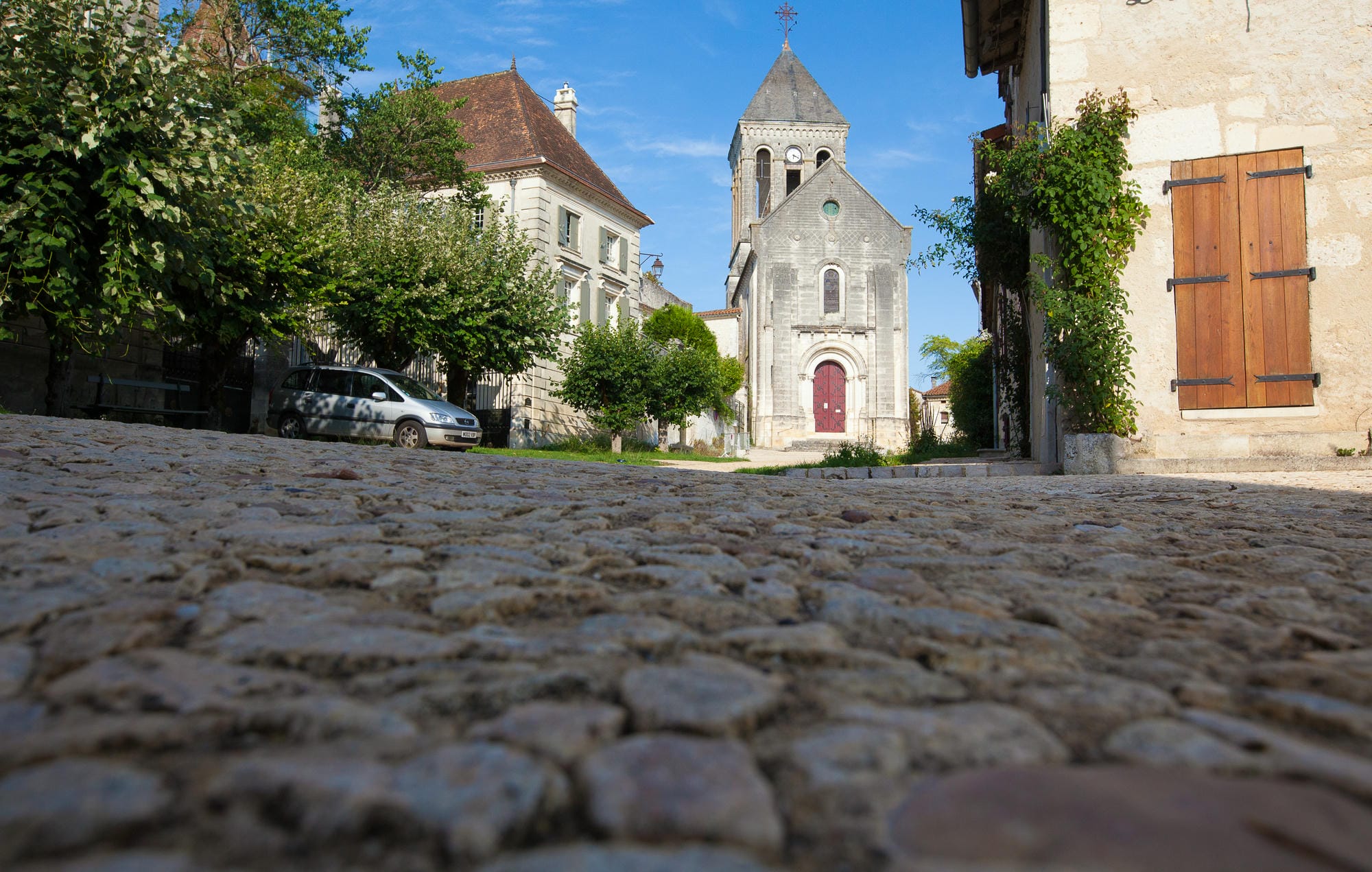 Voiture stationnée dans la rue devant l'église de Bourdeilles