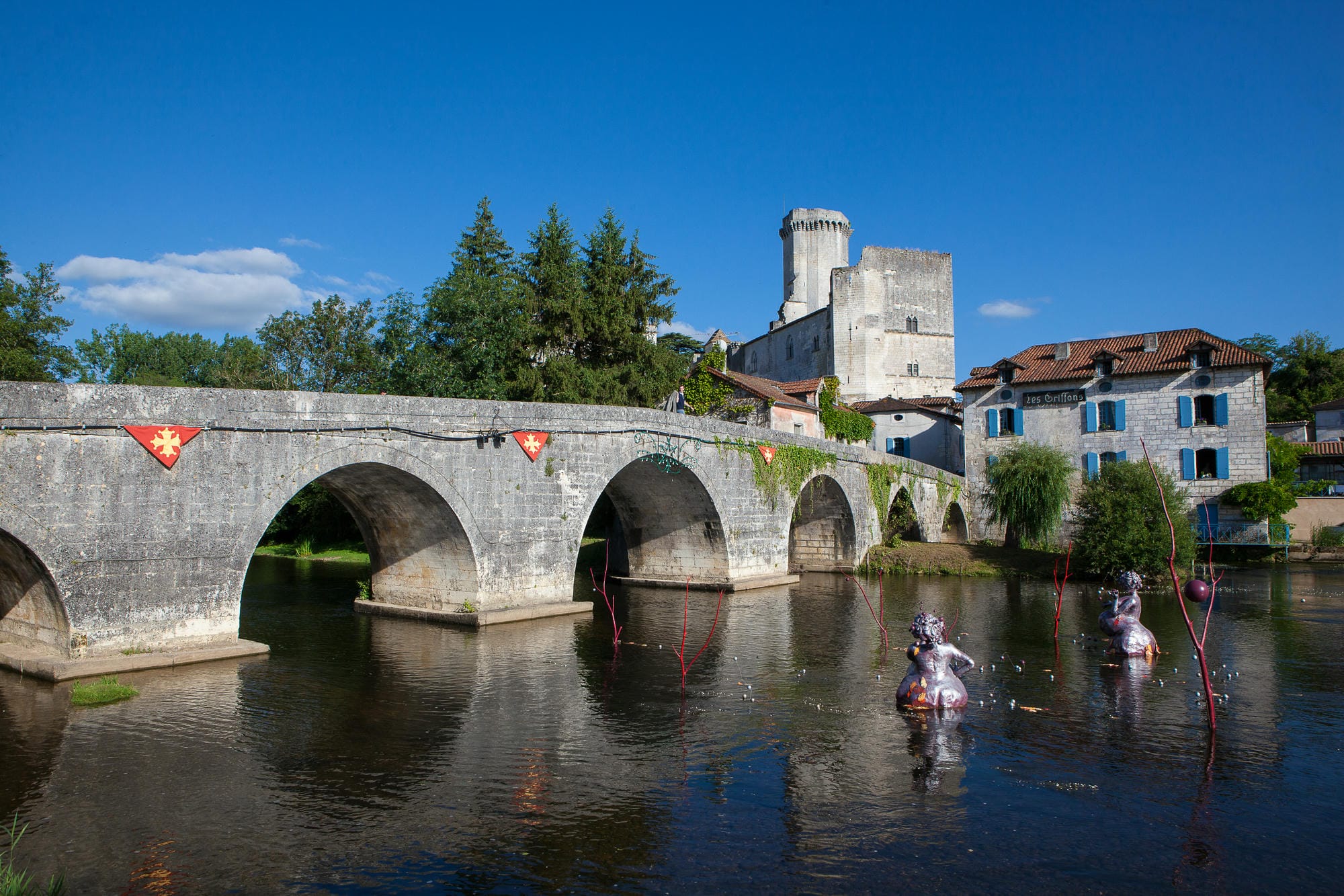 Château de Bourdeilles en arrière-plan sur la Dronne et les Grosses Madames (sculptures des artistes Betty Arab et Laurence Orchard)