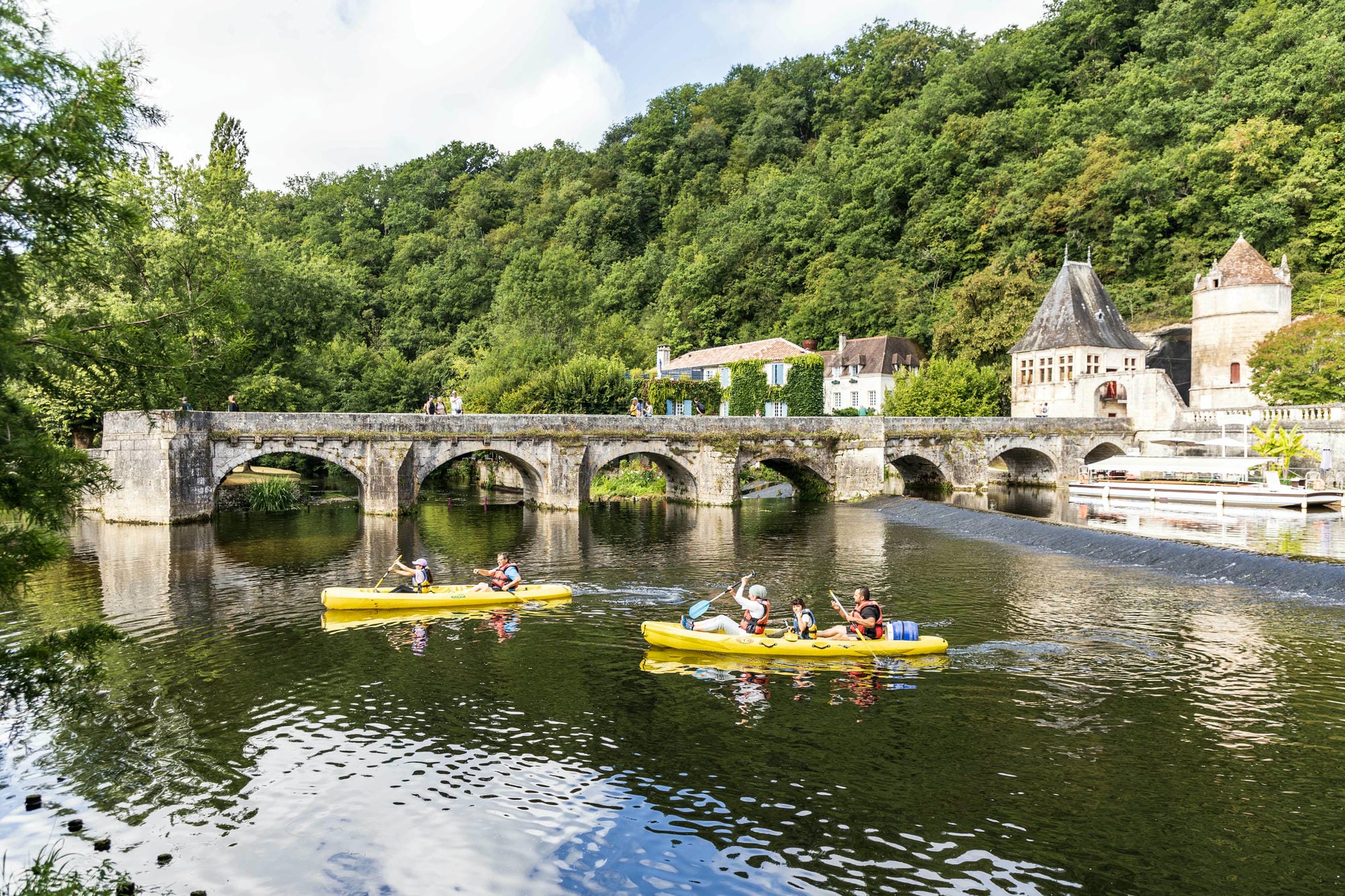 Plusieurs canoës sur la Dronne près d'un pont à Brantôme, activité de plein air