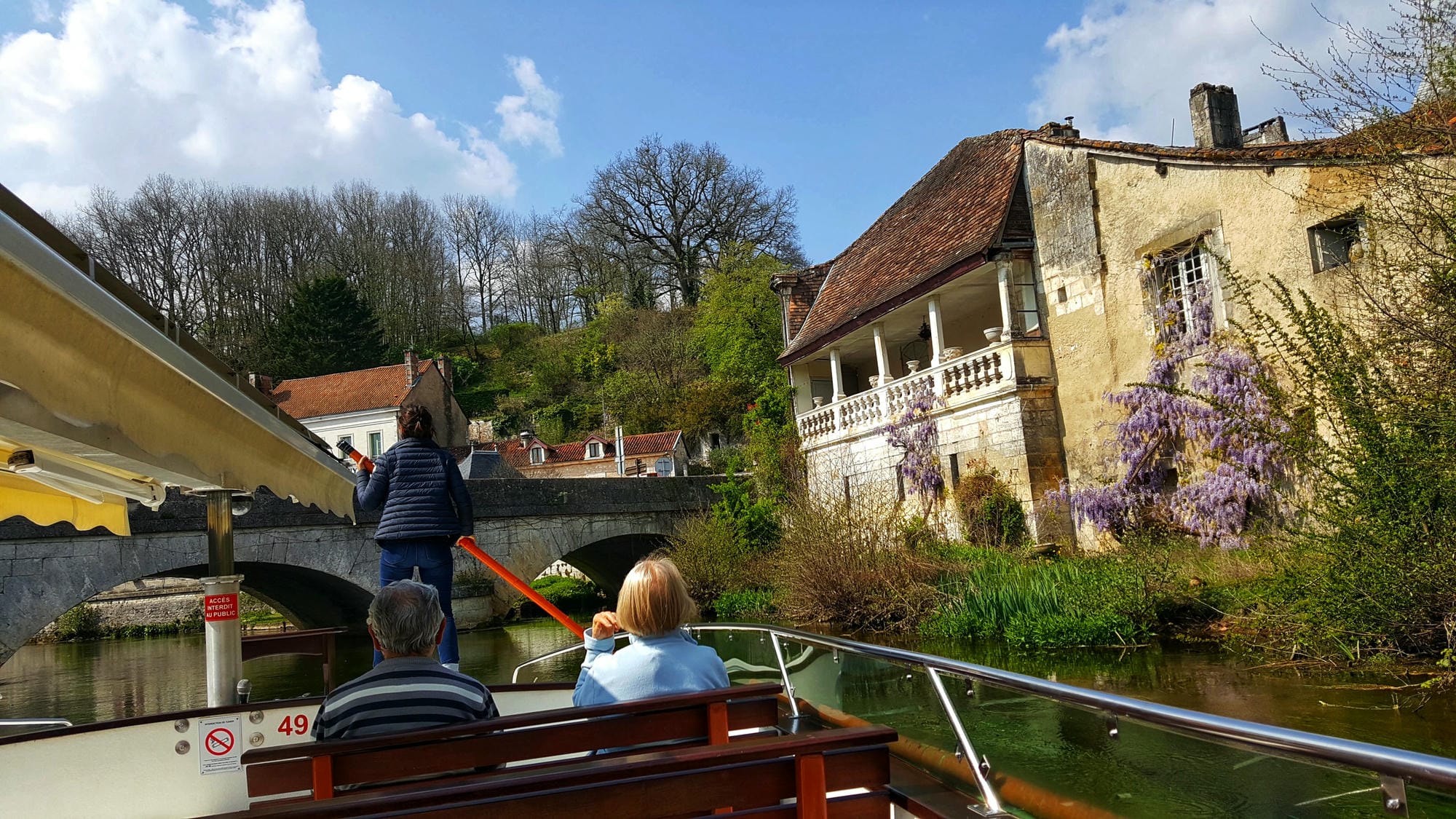 Croisière en bateau électrique sur la Dronne à Brantôme, avec bâtiments historiques en arrière-plan