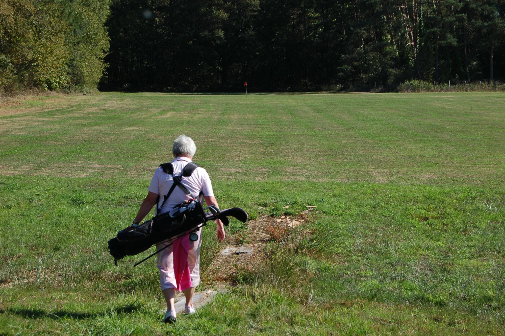 Golfeuse marchant sur le parcours avec son sac de golf à Champs-Romain