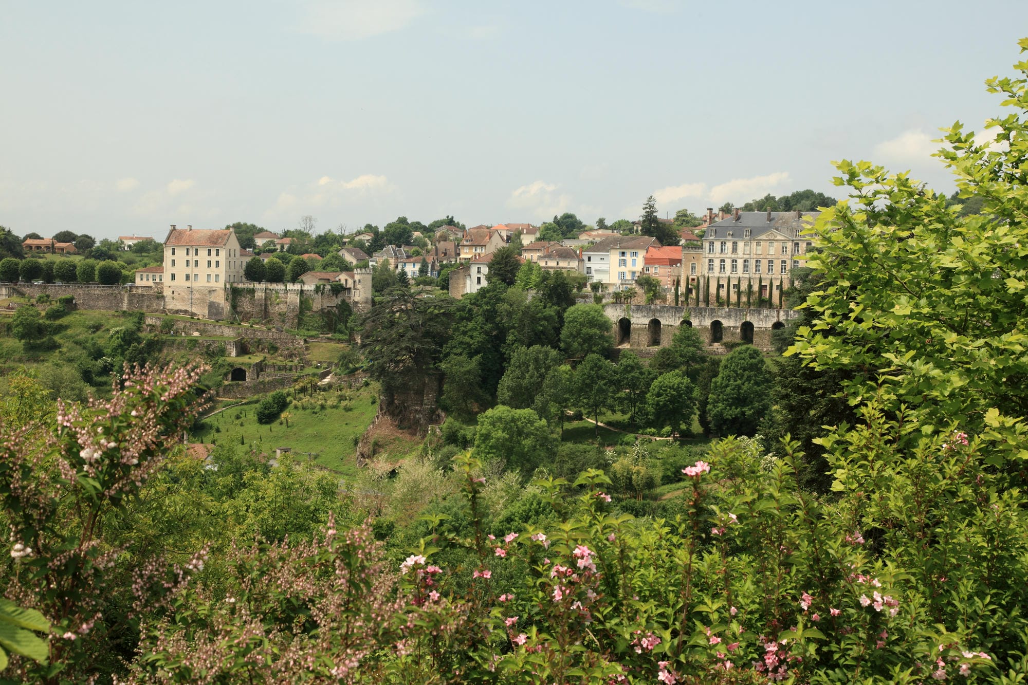 Vue de Nontron avec végétation au premier plan et un pont traversant la ville