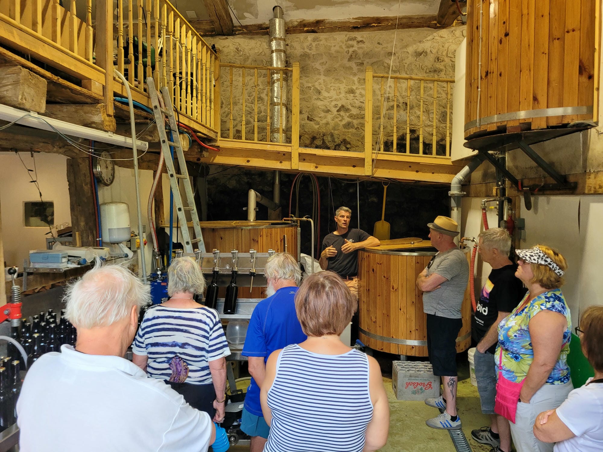 Intérieur de la brasserie de St-Saud avec structure en bois et escalier, visiteurs présents
