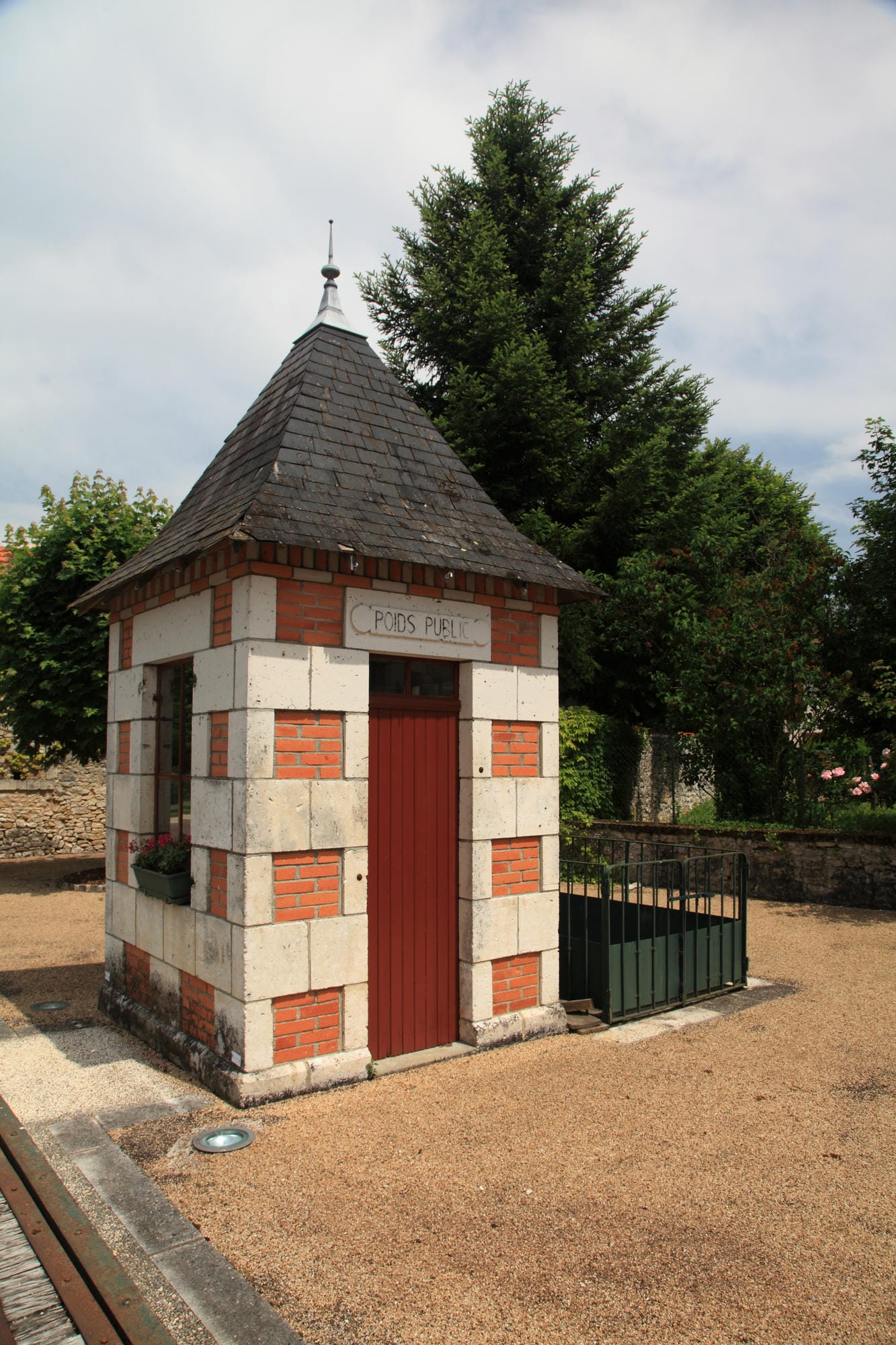 Petite structure en briques avec porte rouge et clôture à Saint-Front-la-Rivière