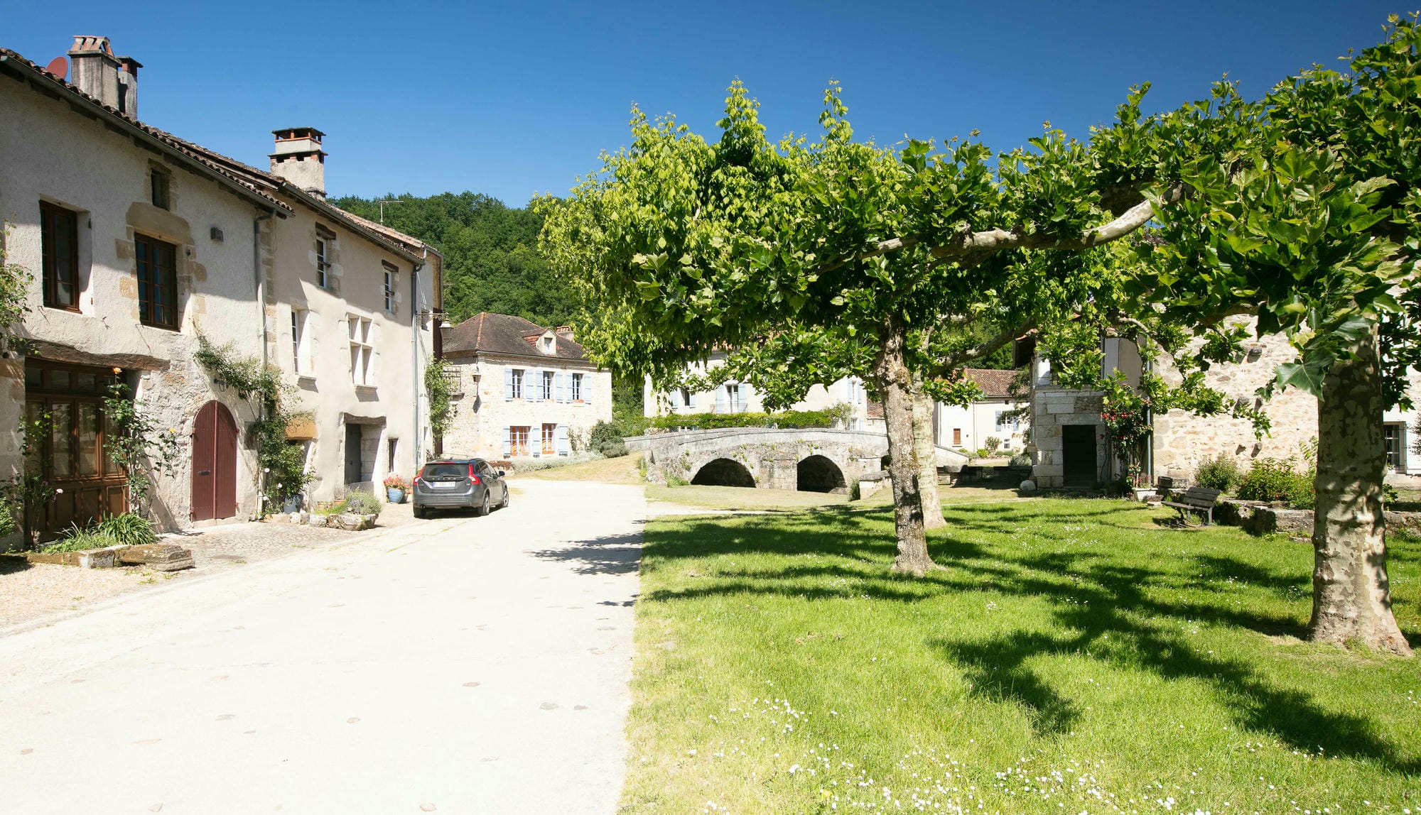 Voiture garée en bord de route devant une maison à St-Jean-de-Côle