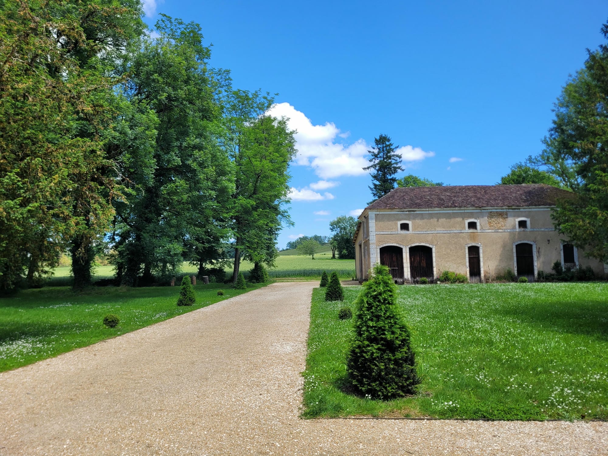 Chemin de gravier menant au Château de la Marthonie (toit marron) à St-Jean-de-Côle