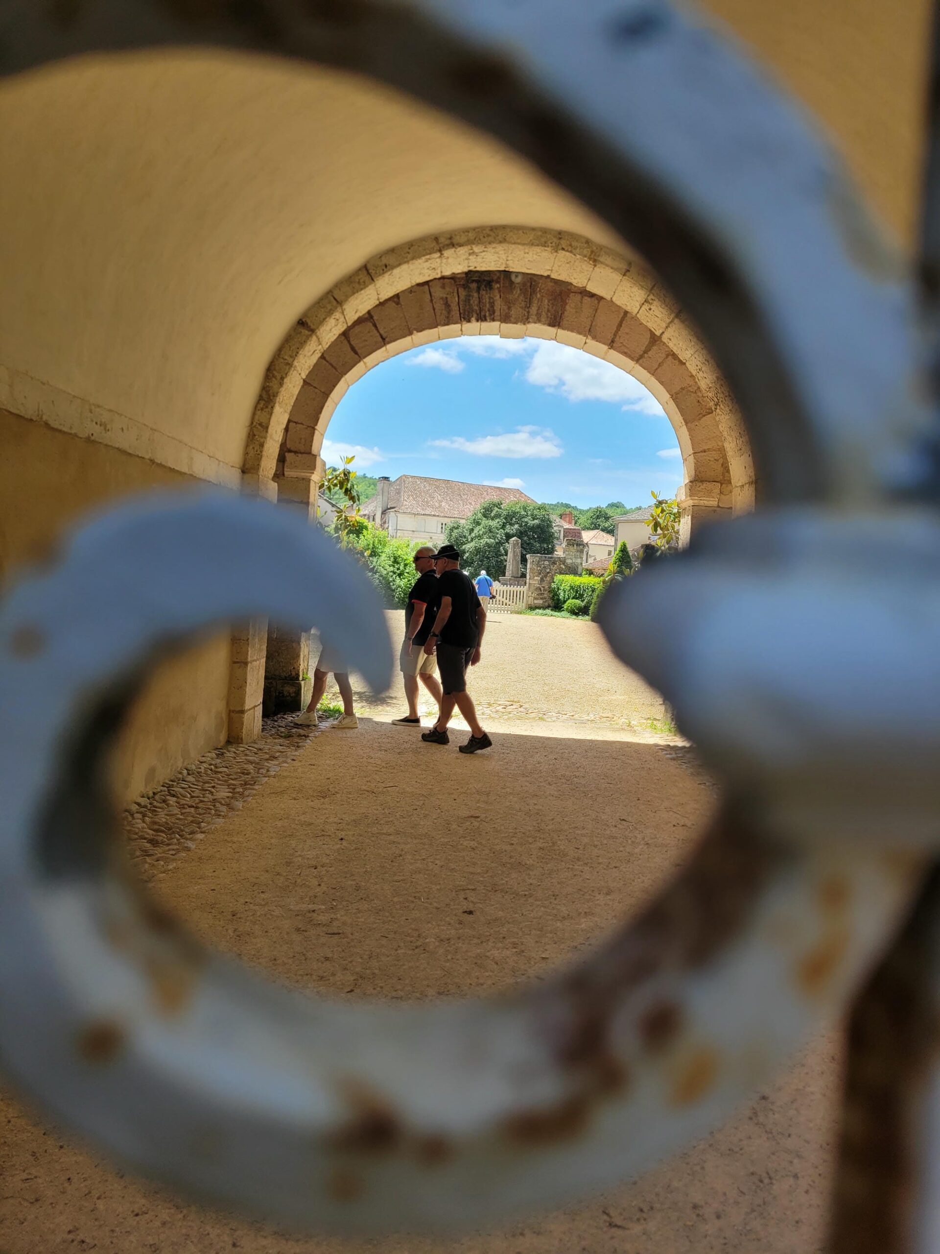 Homme avec sac à dos traversant un passage voûté au Château de la Marthonie, St-Jean-de-Côle