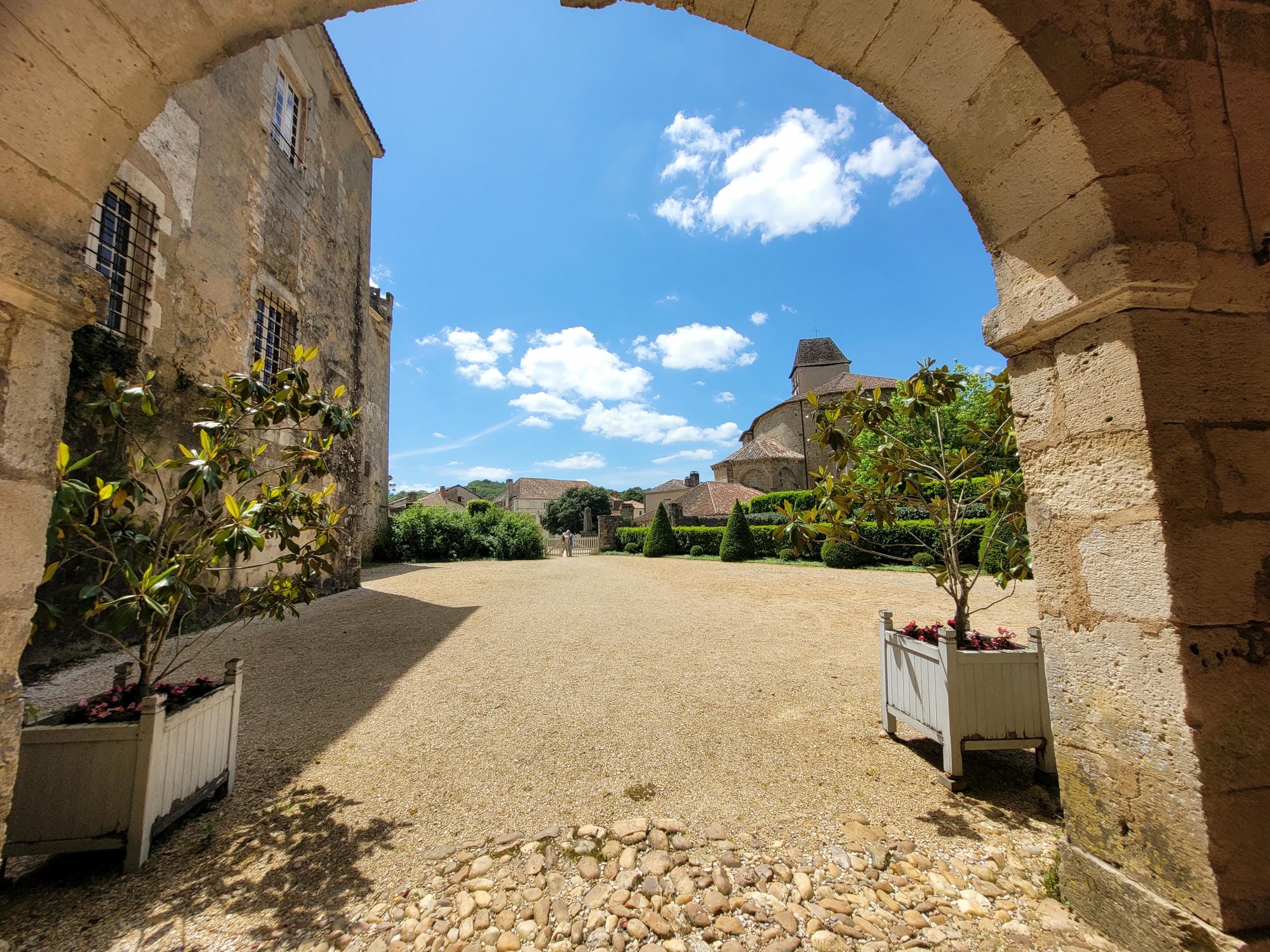 Arche en pierre menant à une cour avec plantes en pots, Château de la Marthonie, St-Jean-de-Côle