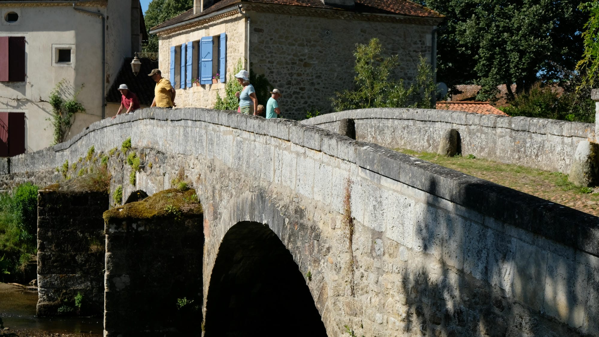 Personnes traversant le pont médiéval sur la Côle à St-Jean-de-Côle